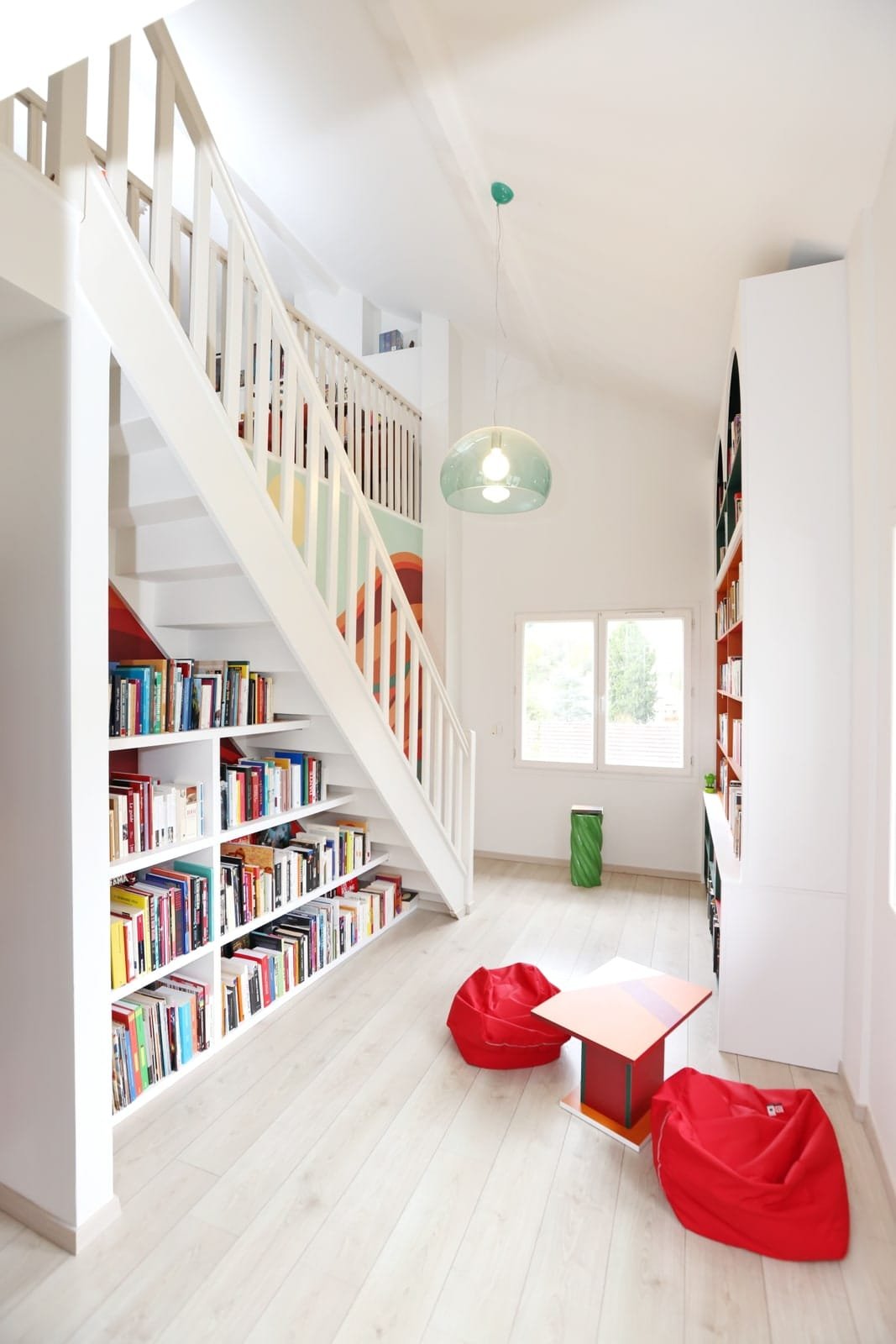 Bibliothèque sur mesure sous escalier avec un coin lecture pour enfants