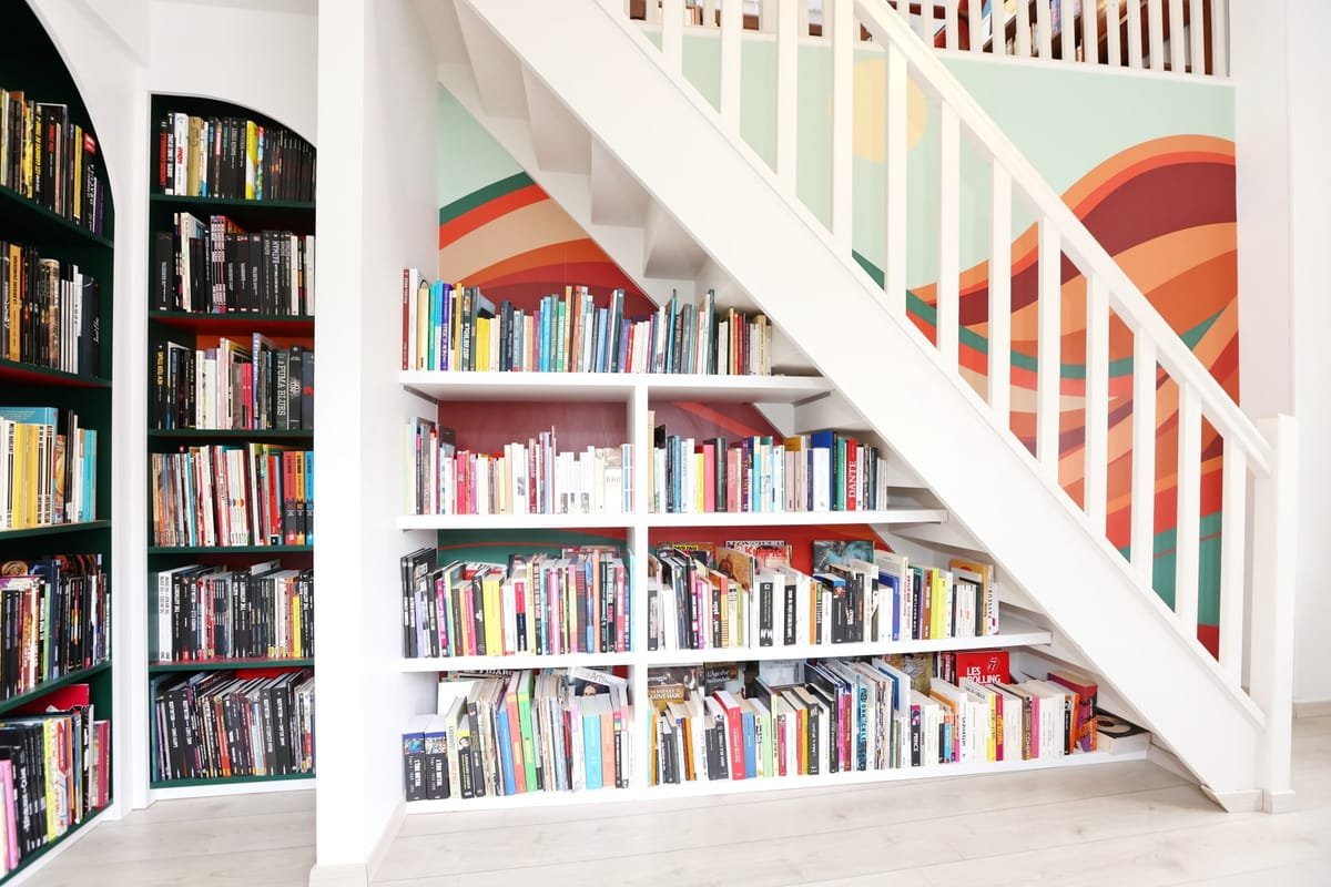 Bibliothèque sur mesure aménagée sous un escalier dans une maison en Isère