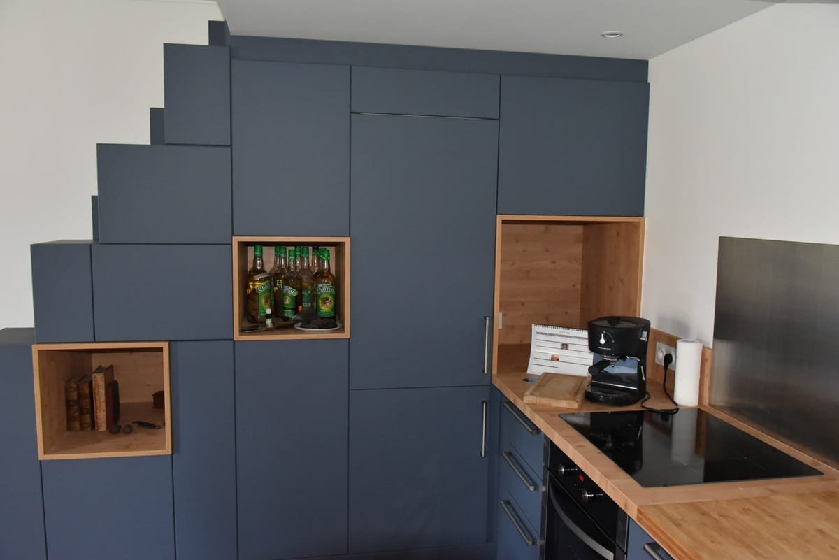 Cuisine moderne sur mesure avec rangements bleus toute hauteur et niches bois