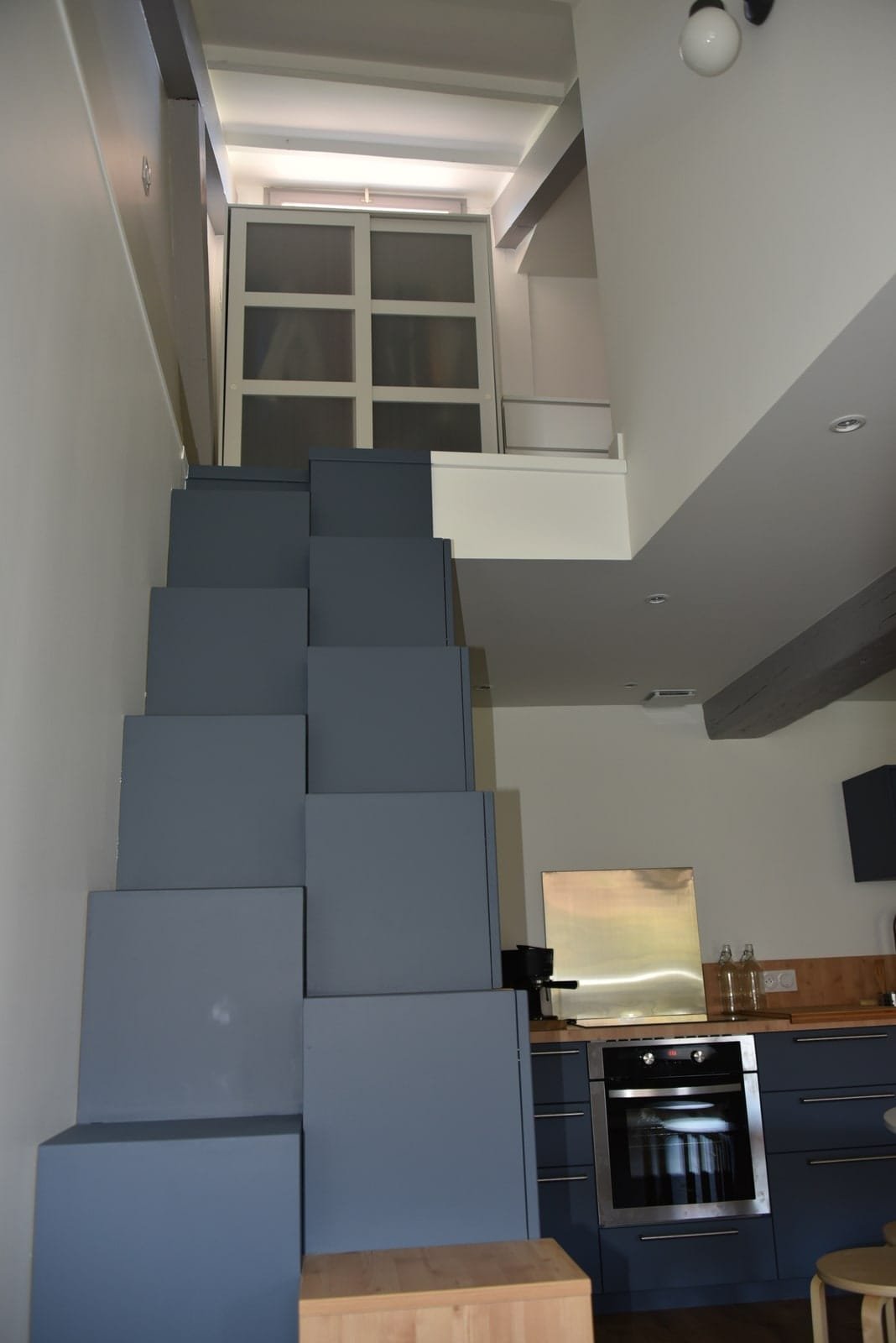 Escalier japonais bleu desservant une mezzanine au-dessus d’une cuisine